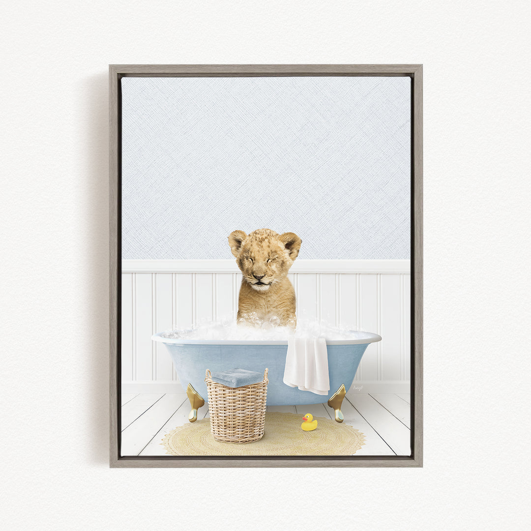 A young lion cub sitting in a blue bathtub filled with water, surrounded by a yellow rubber duck and a basket.