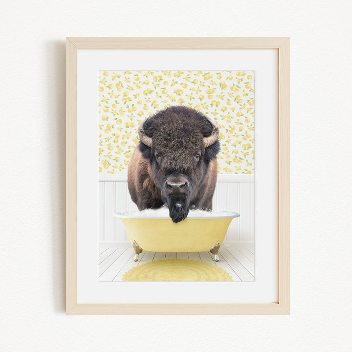 A buffalo standing in a yellow bathtub, with a yellow floral pattern on the wall behind it.