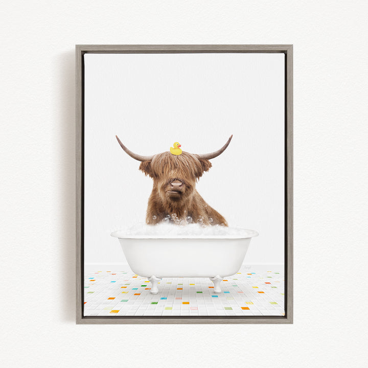 A brown cow with long horns is sitting in a white bathtub filled with bubbles, with a rubber duck perched on its head.