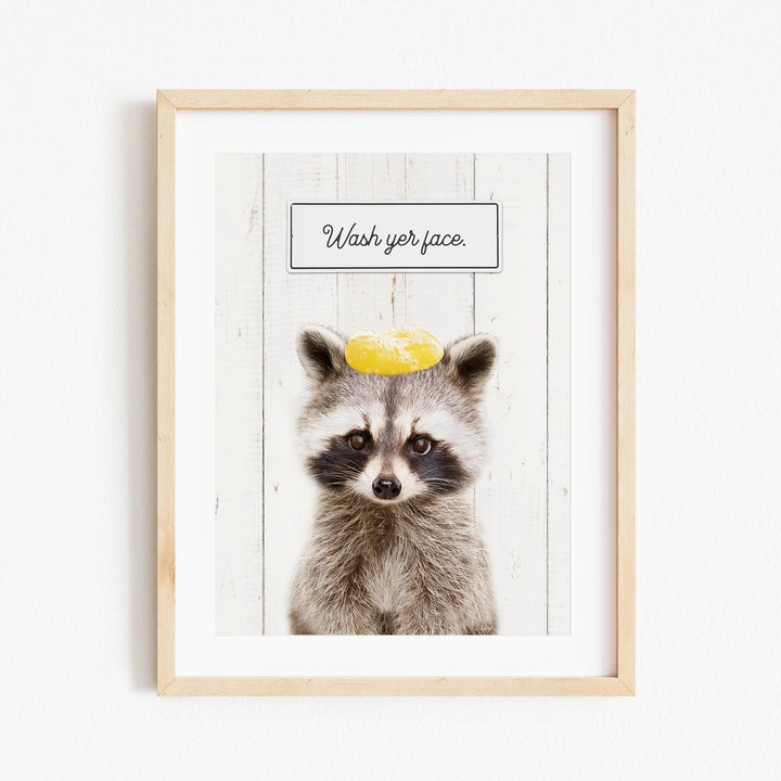 A raccoon wearing a yellow hat with the text "Wash your face" written on it.
