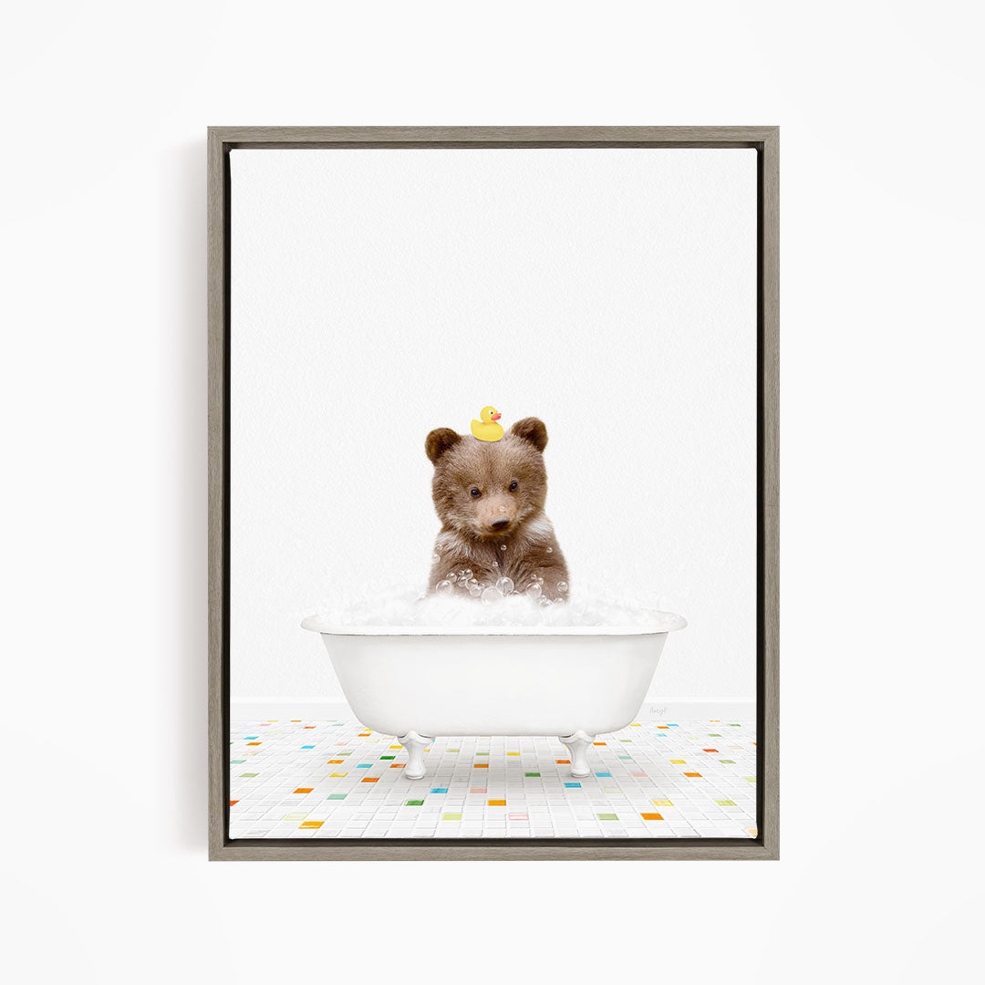 A cute brown bear sitting in a white bathtub filled with bubbles, wearing a yellow rubber duck on its head.