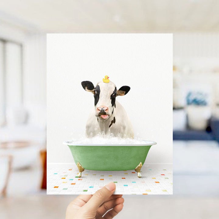 A cow is sitting in a green bathtub filled with bubbles, with a rubber duck perched on its head.