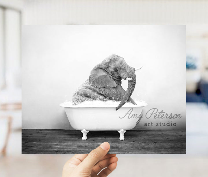 a hand holding up a black and white photo of an elephant in a bathtub