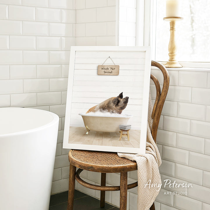 A framed image of a pig sitting in a bathtub, with a sign above it that says "Wash Your Pig".