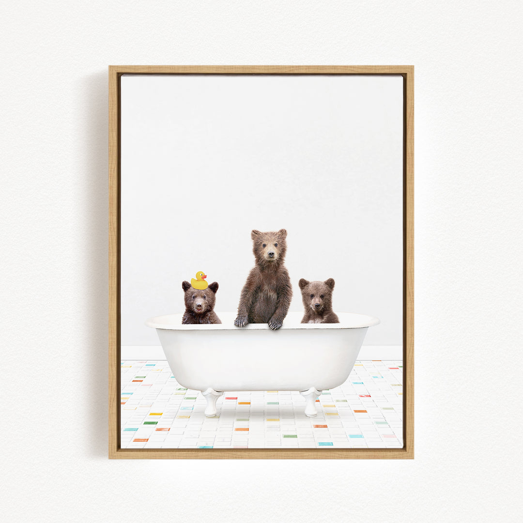 Three adorable brown bears sitting in a white bathtub, with one bear wearing a yellow hat.