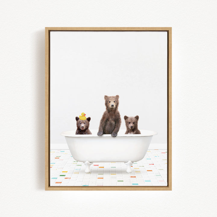 Three adorable brown bears sitting in a white bathtub, with one bear wearing a yellow hat.
