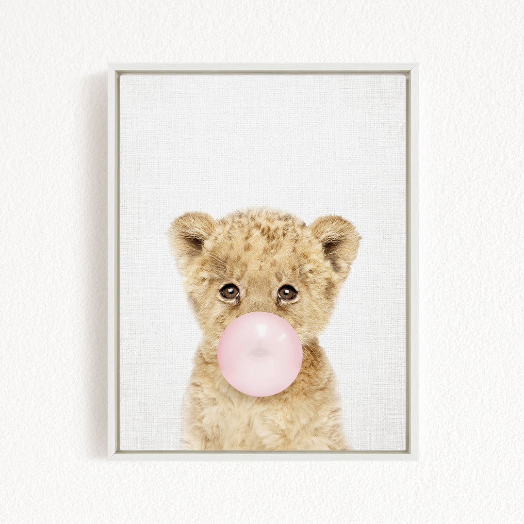 A cute baby lion blowing a bubble with a pink bubble gum bubble.