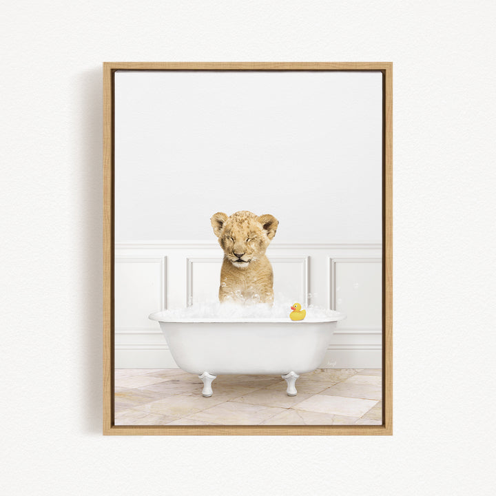 A young lion cub sitting in a white bathtub filled with bubbles, with a rubber duck floating nearby.