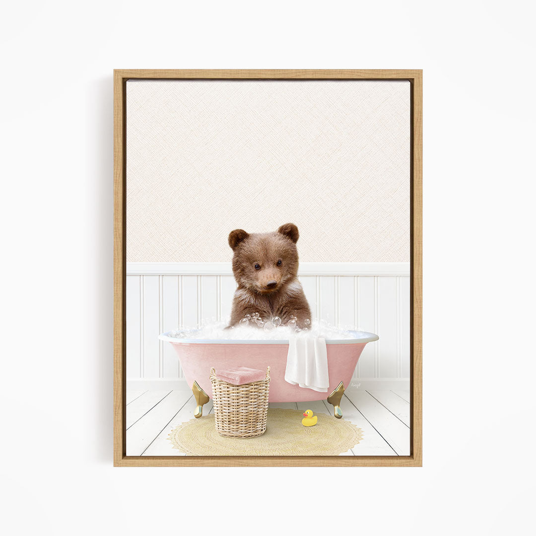 A brown bear sitting in a pink bathtub filled with bubbles, surrounded by a yellow rubber duck and a basket.