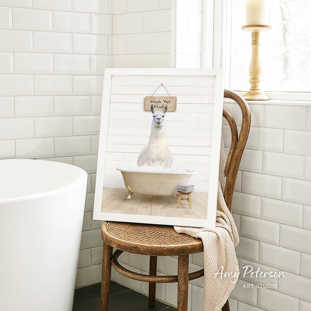 A framed image of a white llama sitting in a bathtub, with a sign above it that says "Wash Your Fluff".