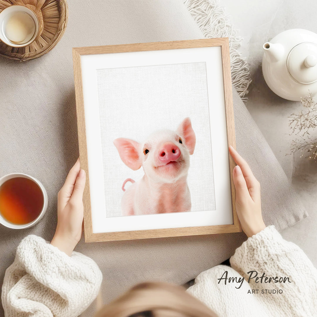 A person is holding a framed picture of a smiling pig, with a teapot, a cup of tea, and a bowl of tea visible in the background.