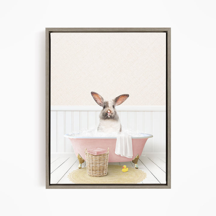 A fluffy white rabbit sits in a pink bathtub filled with bubbles, surrounded by a yellow rubber duck and a wicker basket.