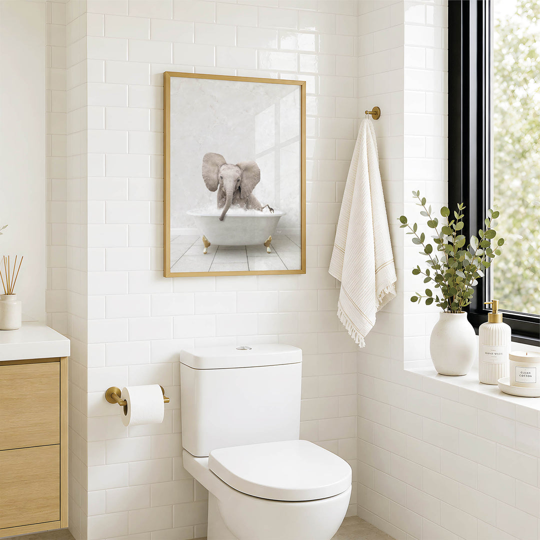 A bathroom with a white toilet, a framed picture of an elephant in a bathtub, and a window with greenery on the sill.