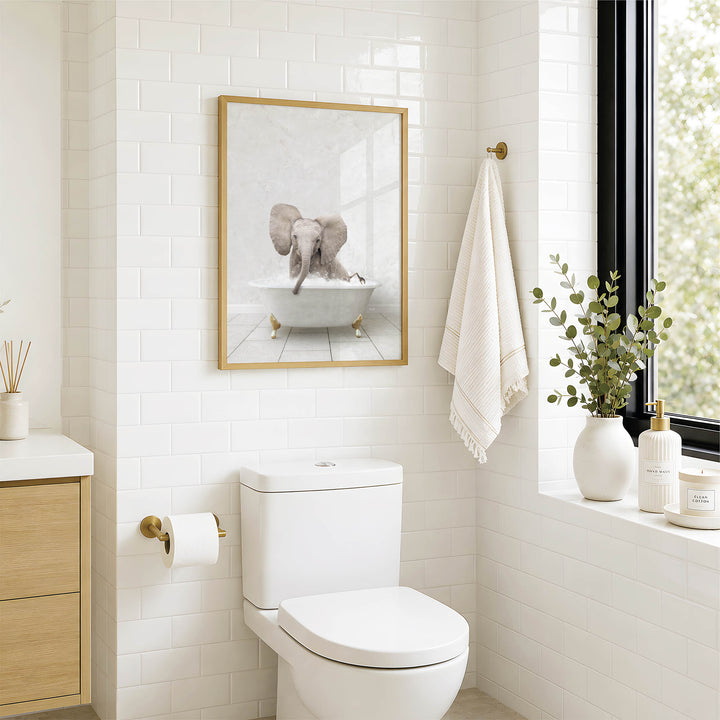 A bathroom with a white toilet, a framed picture of an elephant in a bathtub, and a window with greenery on the sill.