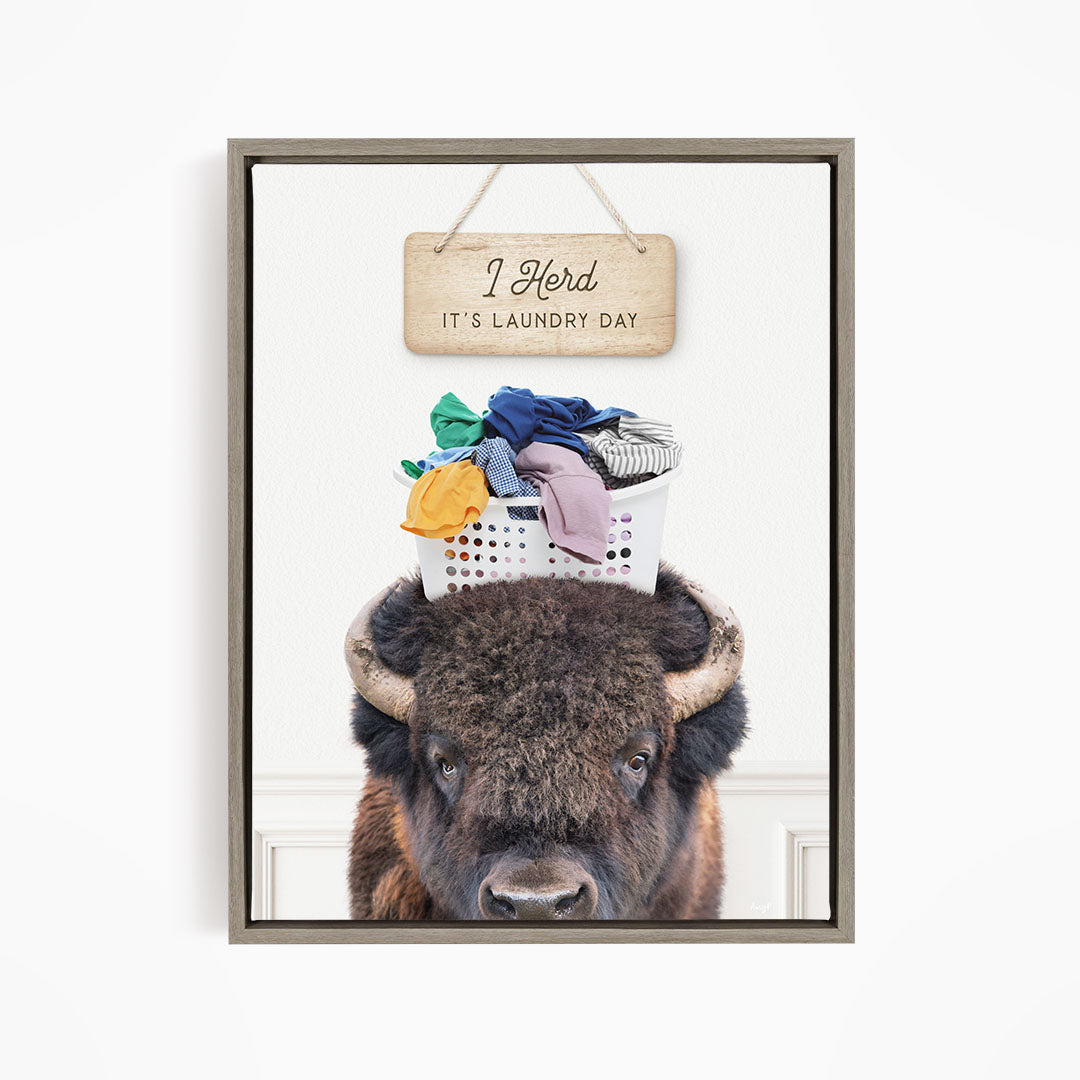 A buffalo with a basket of laundry on its head, accompanied by a wooden sign that says "It's laundry day".