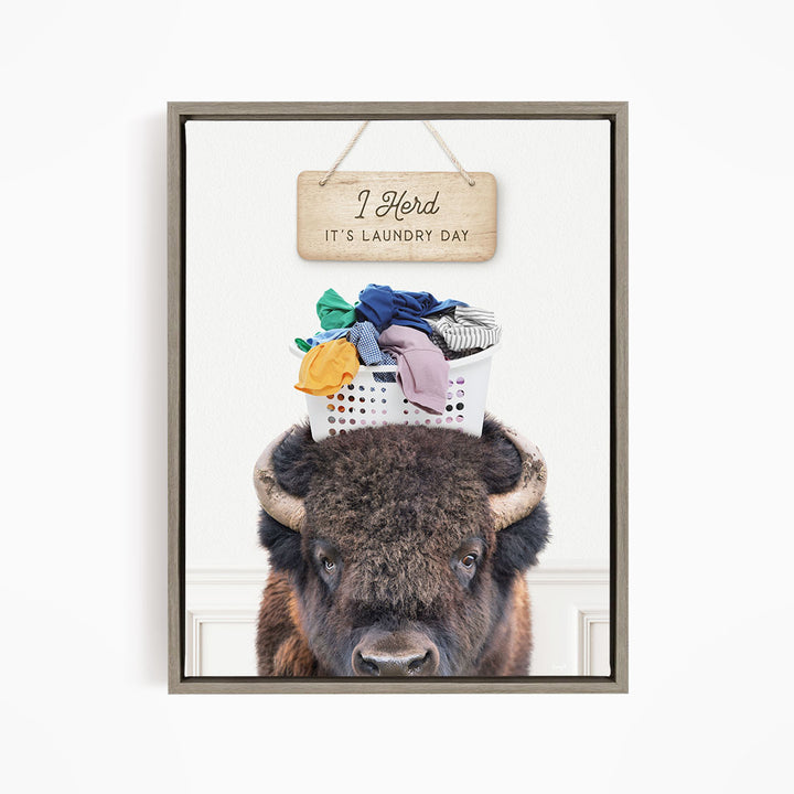 A buffalo with a basket of laundry on its head, accompanied by a wooden sign that says "It's laundry day".