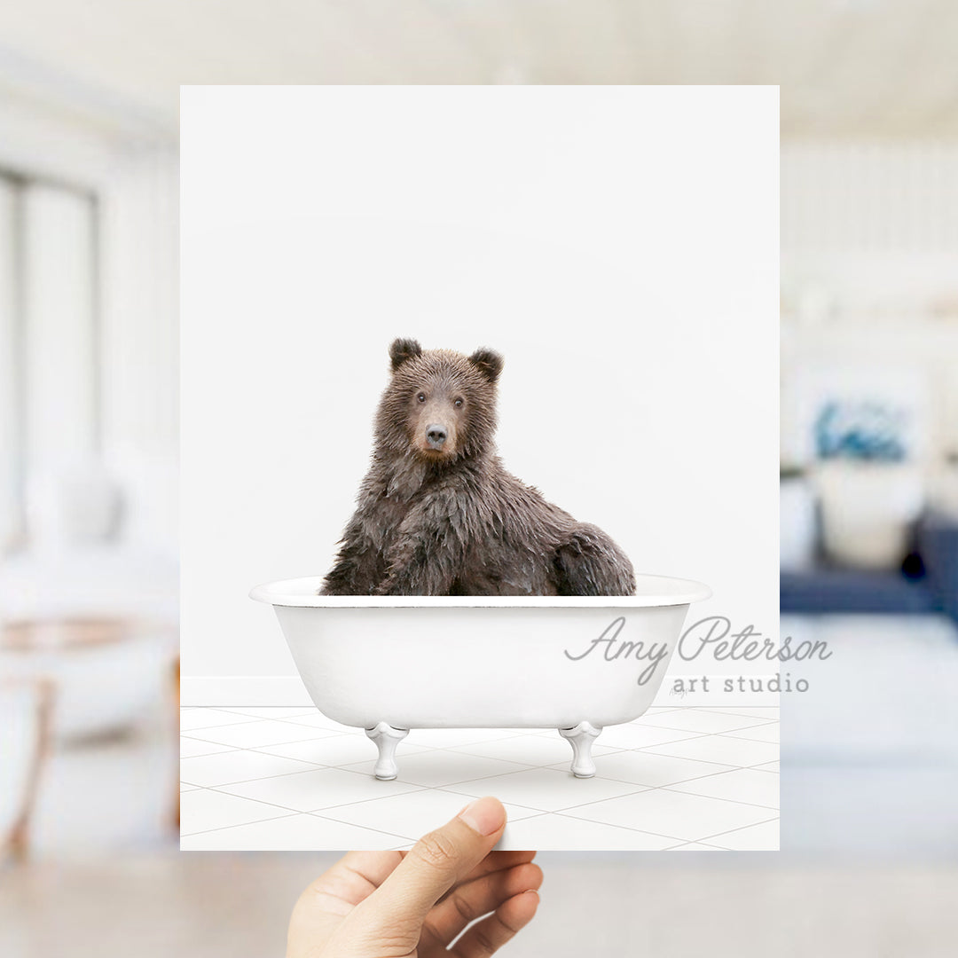 a hand holding a card with a bear in a bathtub