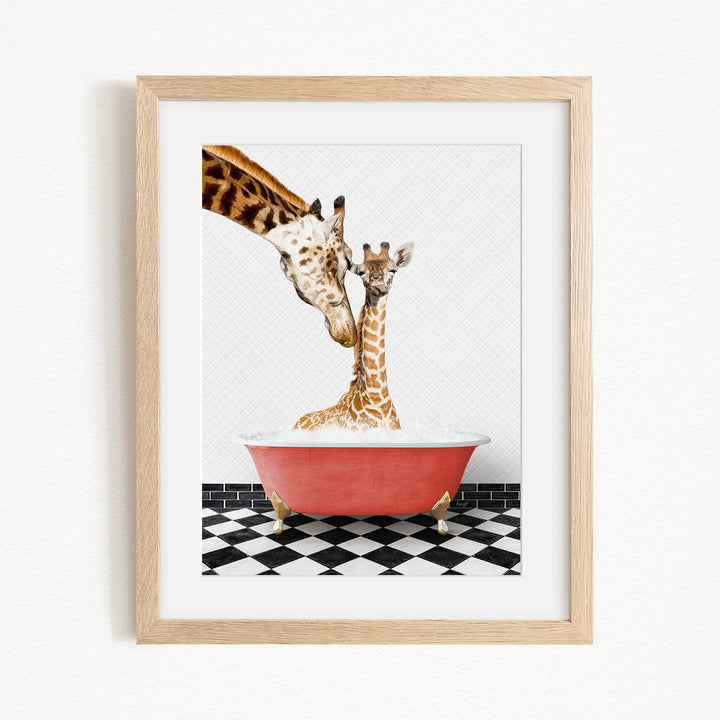 A mother giraffe and her baby giraffe are sitting together in a red bathtub, with the mother gently licking her baby.