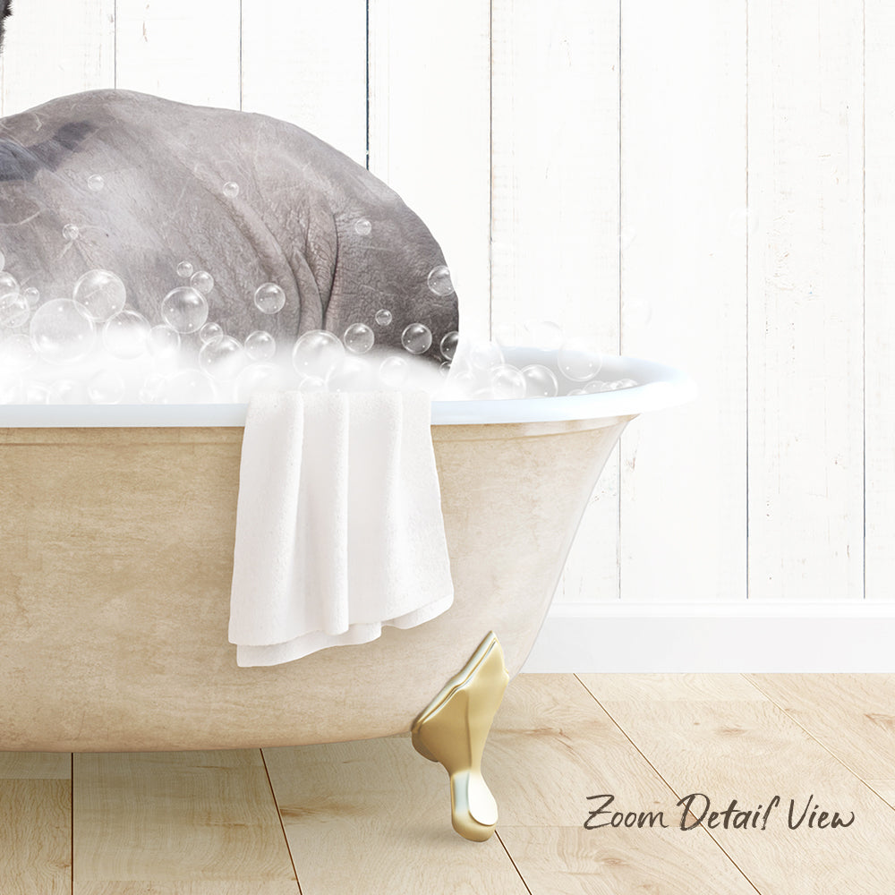 A bathtub filled with bubbles, with a towel hanging on the side and a gold bathtub leg visible.
