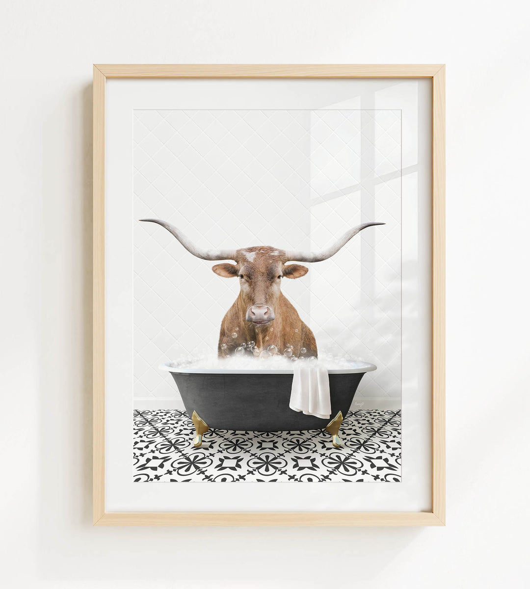 A framed image depicting a bull with long horns sitting in a bathtub filled with bubbles.