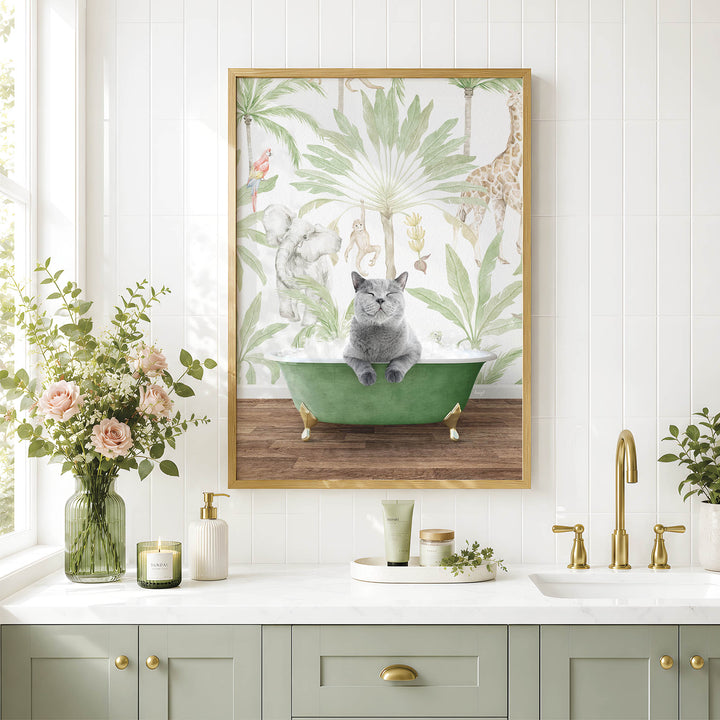 A framed picture of a cat sitting in a green bathtub, surrounded by tropical plants, is displayed on a white tiled wall above a bathroom vanity with a sink and gold faucets.