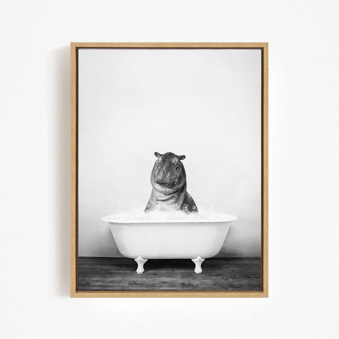 A black and white photograph of a hippopotamus sitting in a bathtub filled with water.