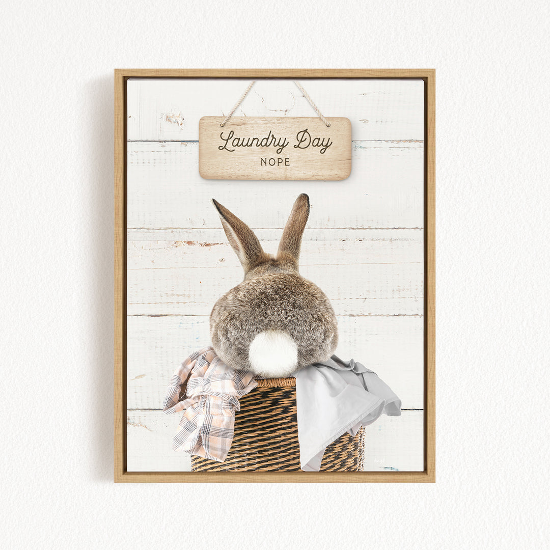 A wooden sign with the text "Laundry Day Hope" hangs above a basket containing a plaid blanket and a gray garment.