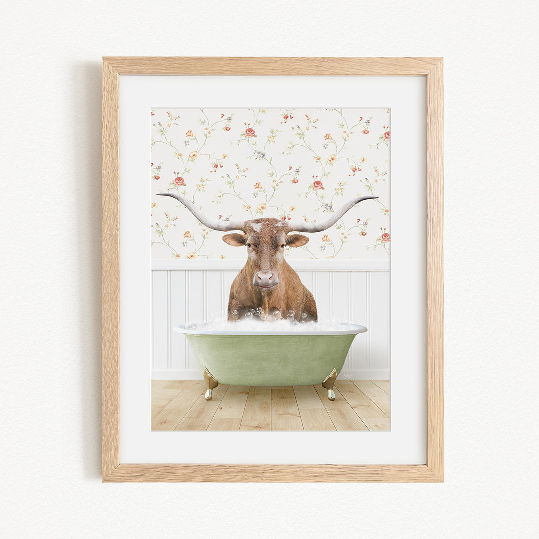 A brown cow with large horns is sitting in a green bathtub filled with water, surrounded by a floral patterned wall.