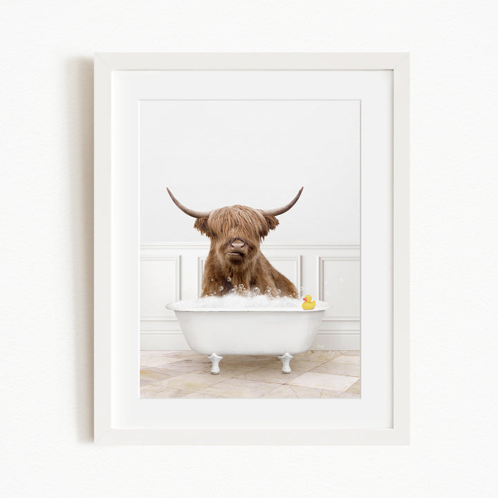 A brown cow with long horns is sitting in a white bathtub filled with water, with a yellow rubber duck floating in the tub.