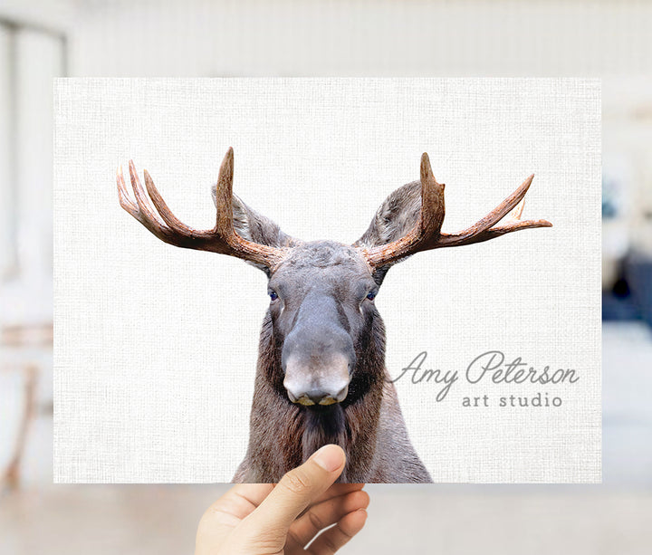 a hand holding up a picture of a moose