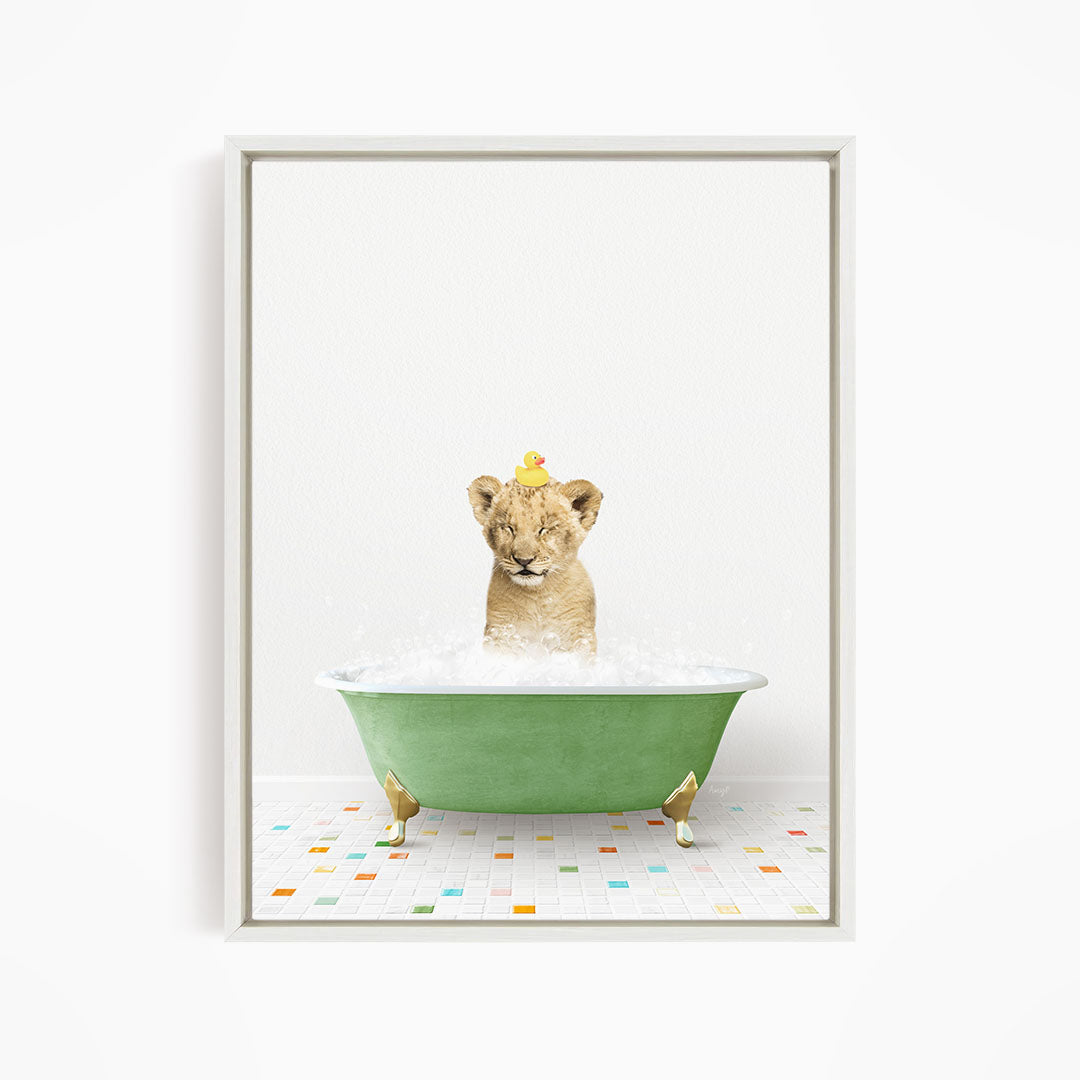 A young lion cub is sitting in a green bathtub filled with water, with a yellow rubber duck perched on its head.