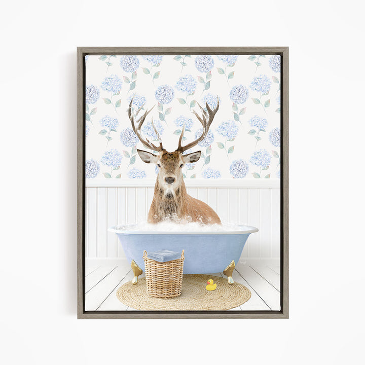 A deer with antlers is sitting in a blue bathtub filled with water, surrounded by a wicker basket and yellow rubber ducks.