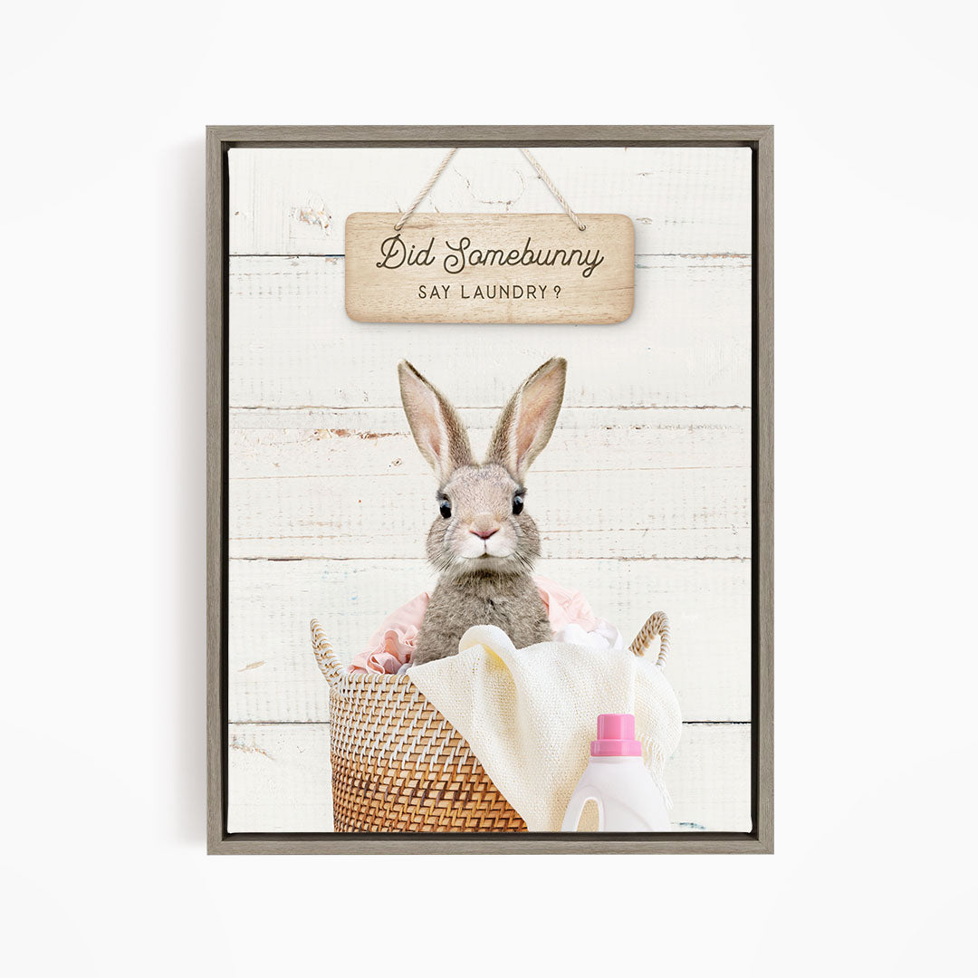 A cute rabbit sitting in a woven laundry basket, with a sign above that says "Did Somebunny Sat Laundry?".