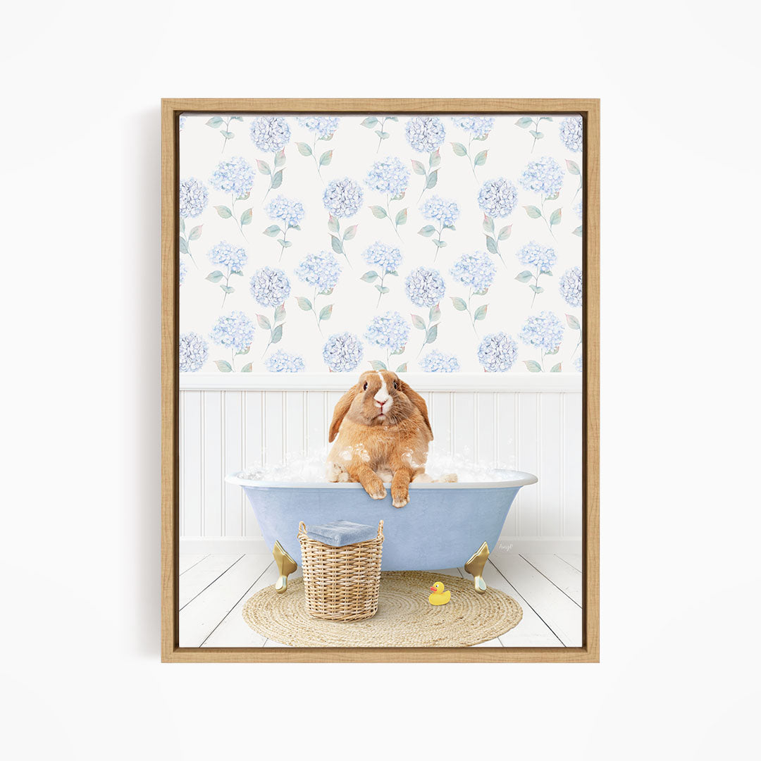 A brown rabbit sitting in a blue bathtub filled with water, surrounded by a wicker basket and rubber duckies.