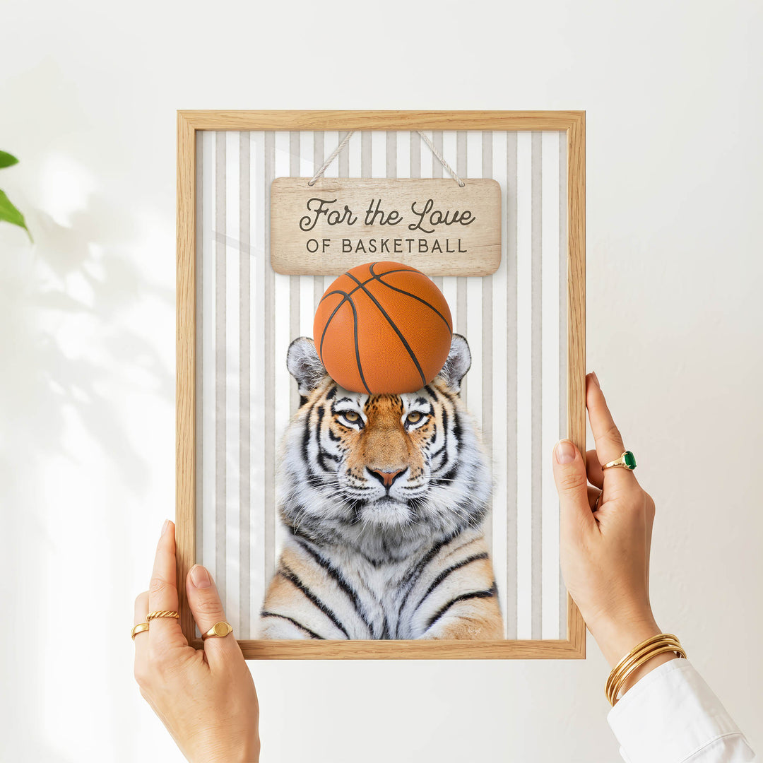 A person's hands are holding a framed picture of a tiger with a basketball on its head.