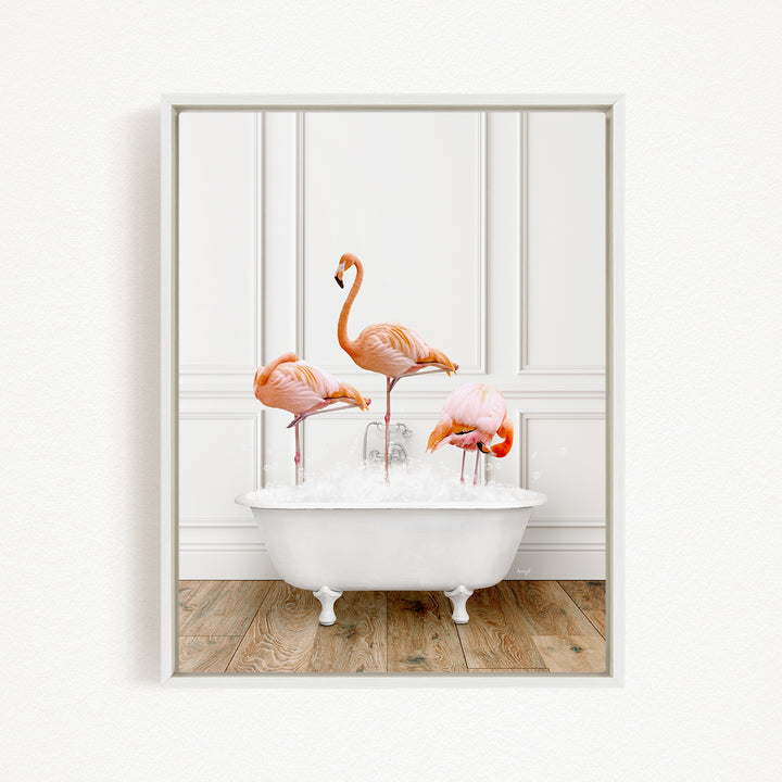 A framed image of three flamingos standing in a white bathtub filled with water.