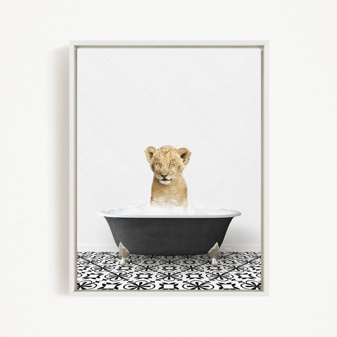 A young lion cub is sitting in a black bathtub filled with water, looking up at the camera with its eyes closed.