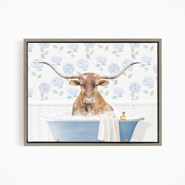 A brown cow with large horns is sitting in a blue bathtub filled with bubbles, surrounded by a floral patterned wall.