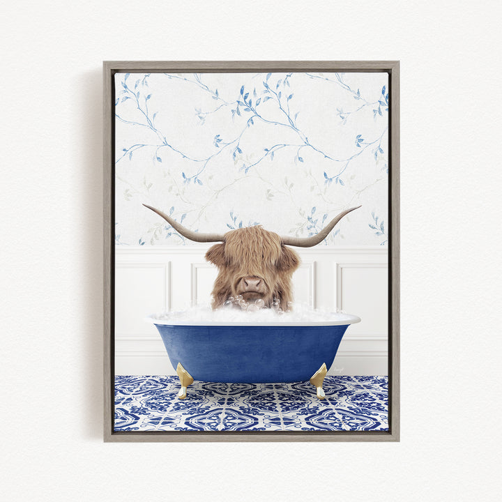 A framed image depicting a Highland cow with long horns sitting in a blue bathtub, surrounded by a blue and white patterned rug.