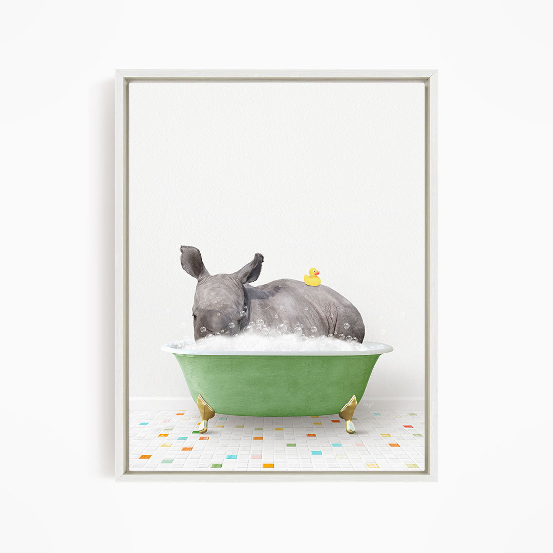 A rhinoceros is sitting in a green bathtub filled with bubbles, with a yellow rubber duck floating on its back.
