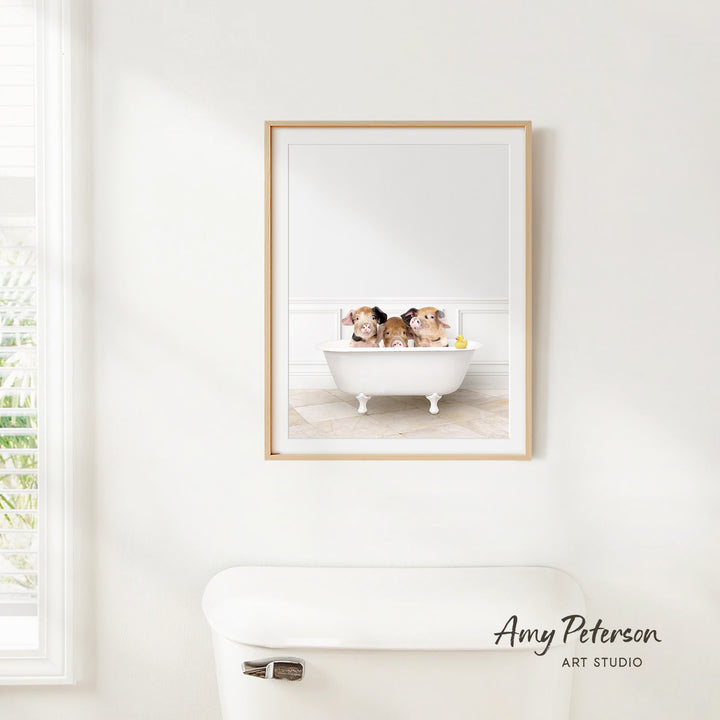 A framed photograph of three dogs sitting in a bathtub, with a window and a toilet visible in the background.