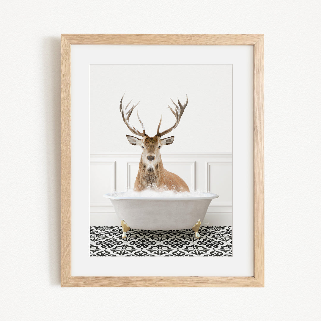 A deer with large antlers is sitting in a white bathtub filled with water, surrounded by a black and white patterned rug.