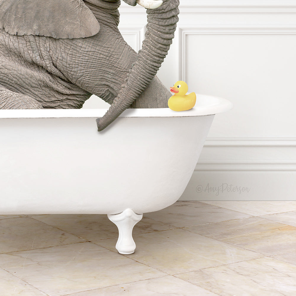 A gray elephant is sitting in a white bathtub, with a yellow rubber duck resting on the edge of the tub.