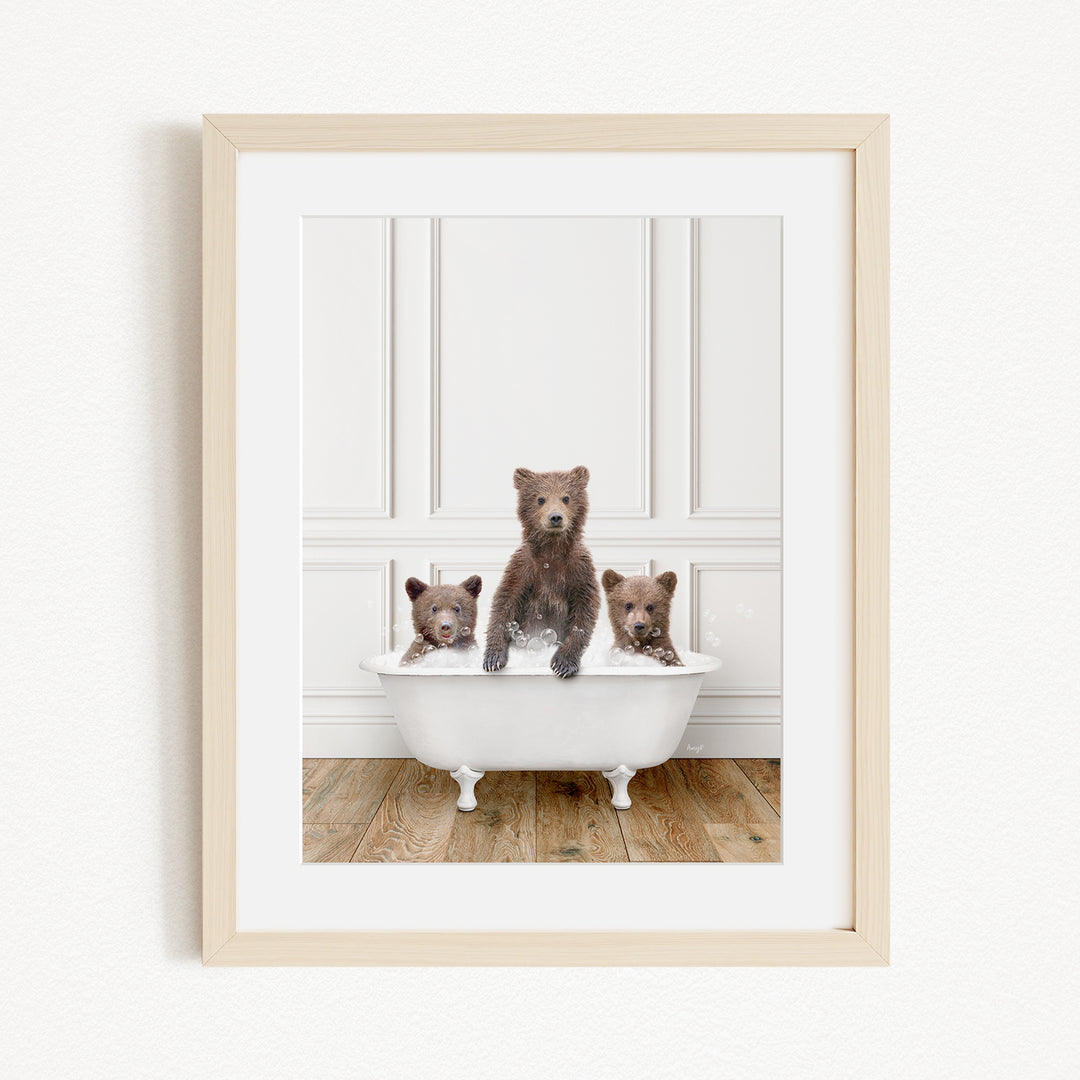 A framed image of three brown bears sitting in a white bathtub, with one bear sitting in the center and the other two bears sitting on either side.