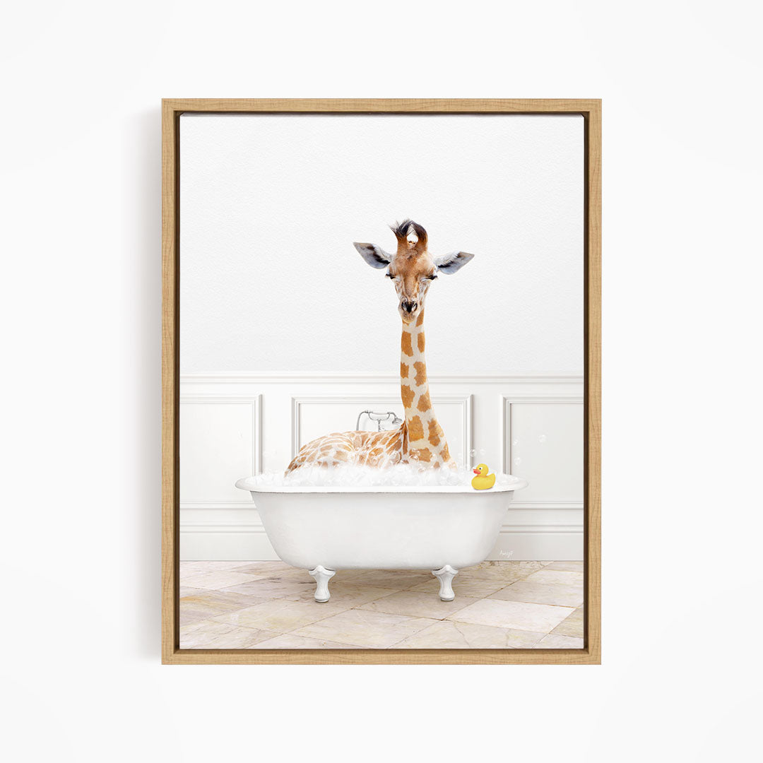A giraffe sitting in a white bathtub filled with bubbles, with a yellow rubber duck floating in the water.