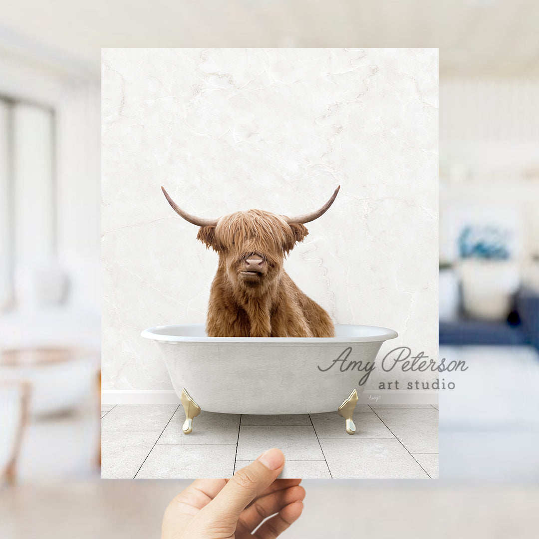 a hand holding up a photo of a bull in a bathtub