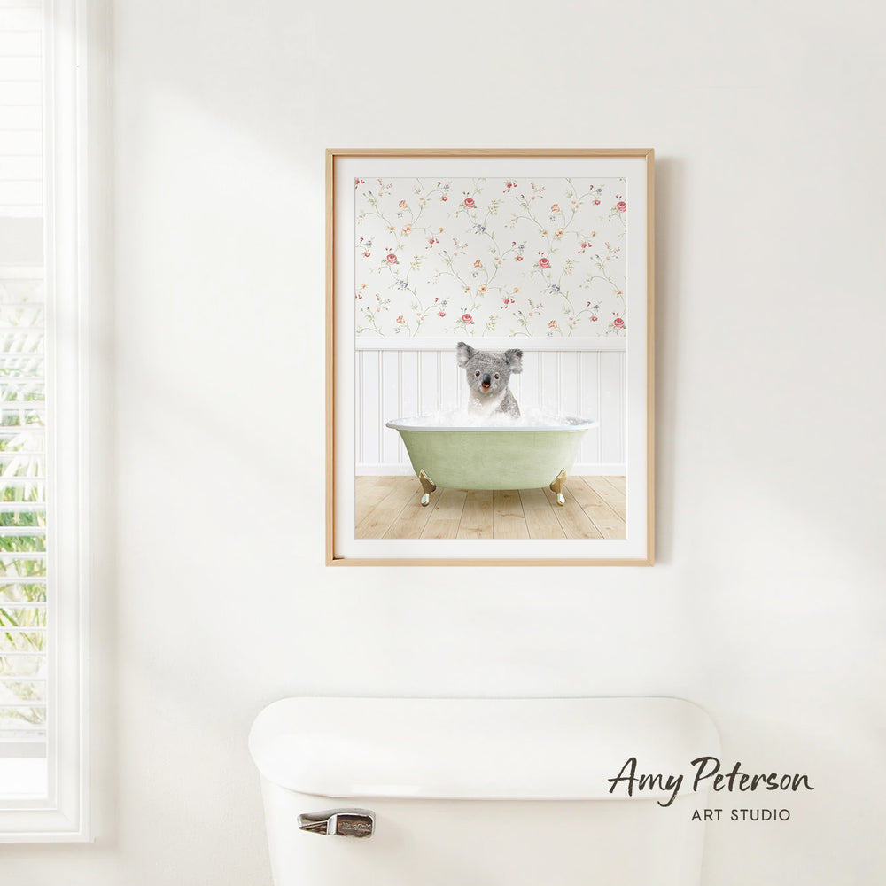 A framed image of a koala bear sitting in a bathtub, surrounded by a floral pattern on the wall behind it.