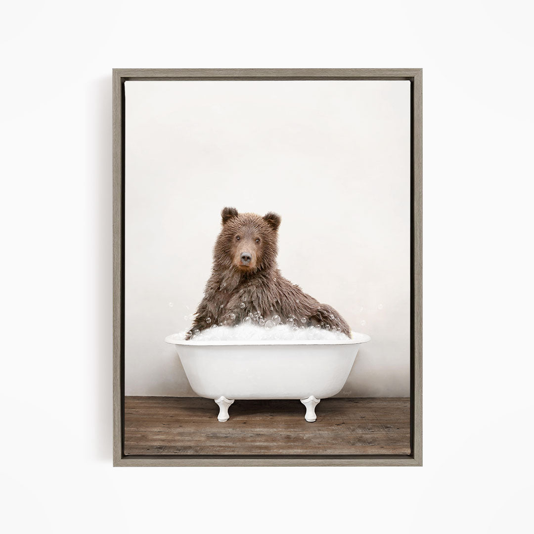A brown bear sitting in a white bathtub filled with water, looking directly at the camera.