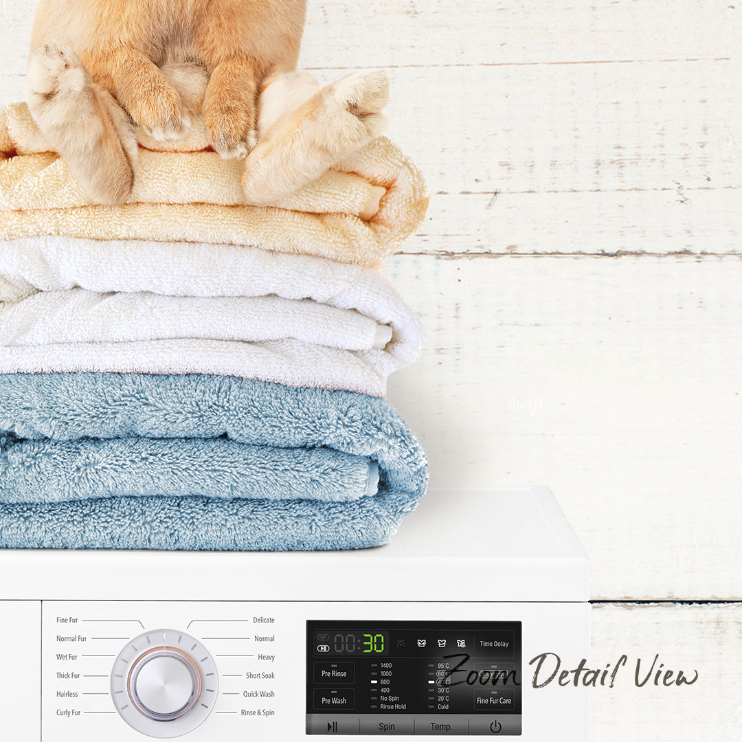 A stack of folded towels on a white surface, with a cat sitting on top of the towels.