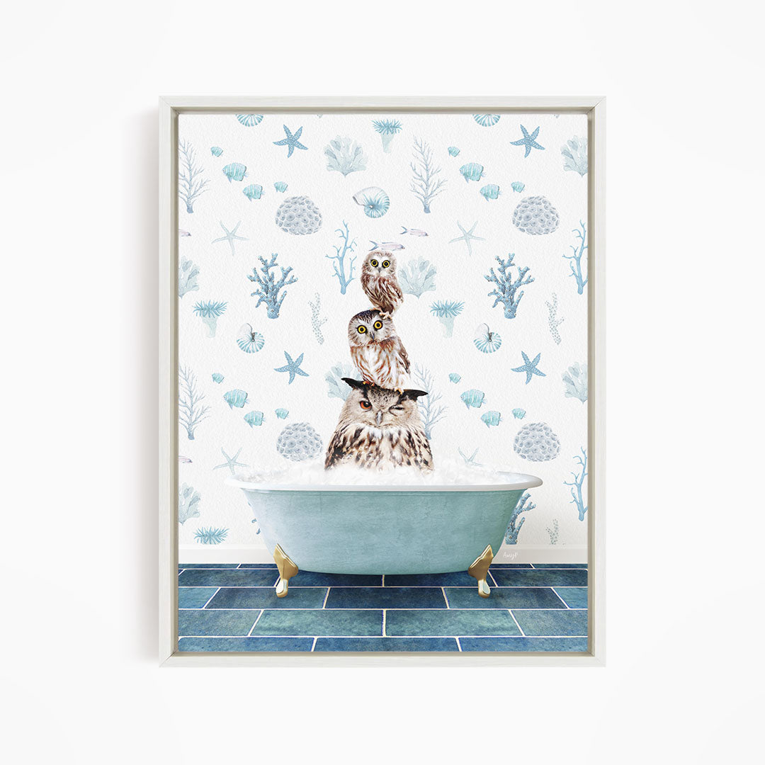 A framed print depicting a whimsical scene of three owls sitting in a bathtub, surrounded by a blue and white ocean-themed wallpaper.